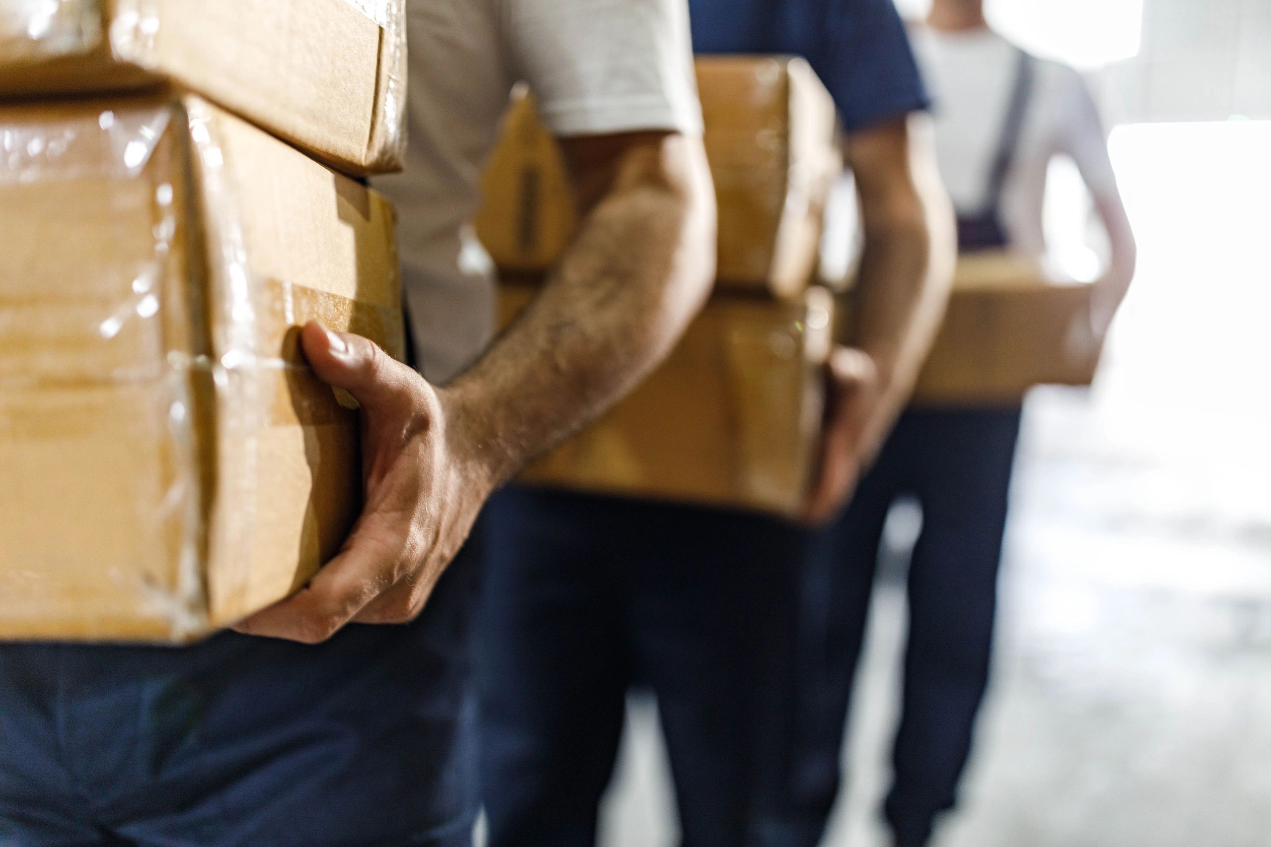 Workers carrying cartons in a warehouse-style setting