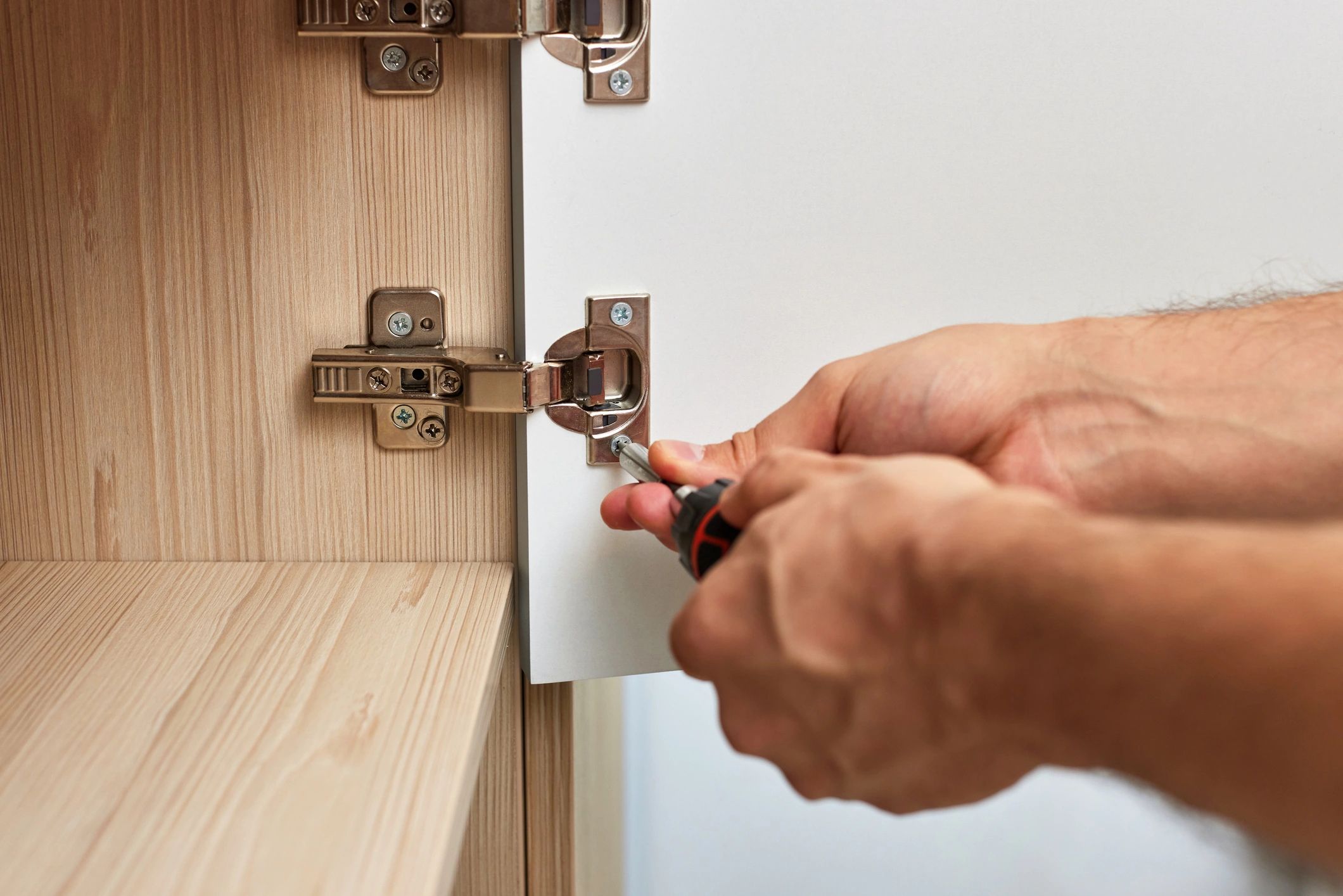 Handyman repairing a cabinet hinge