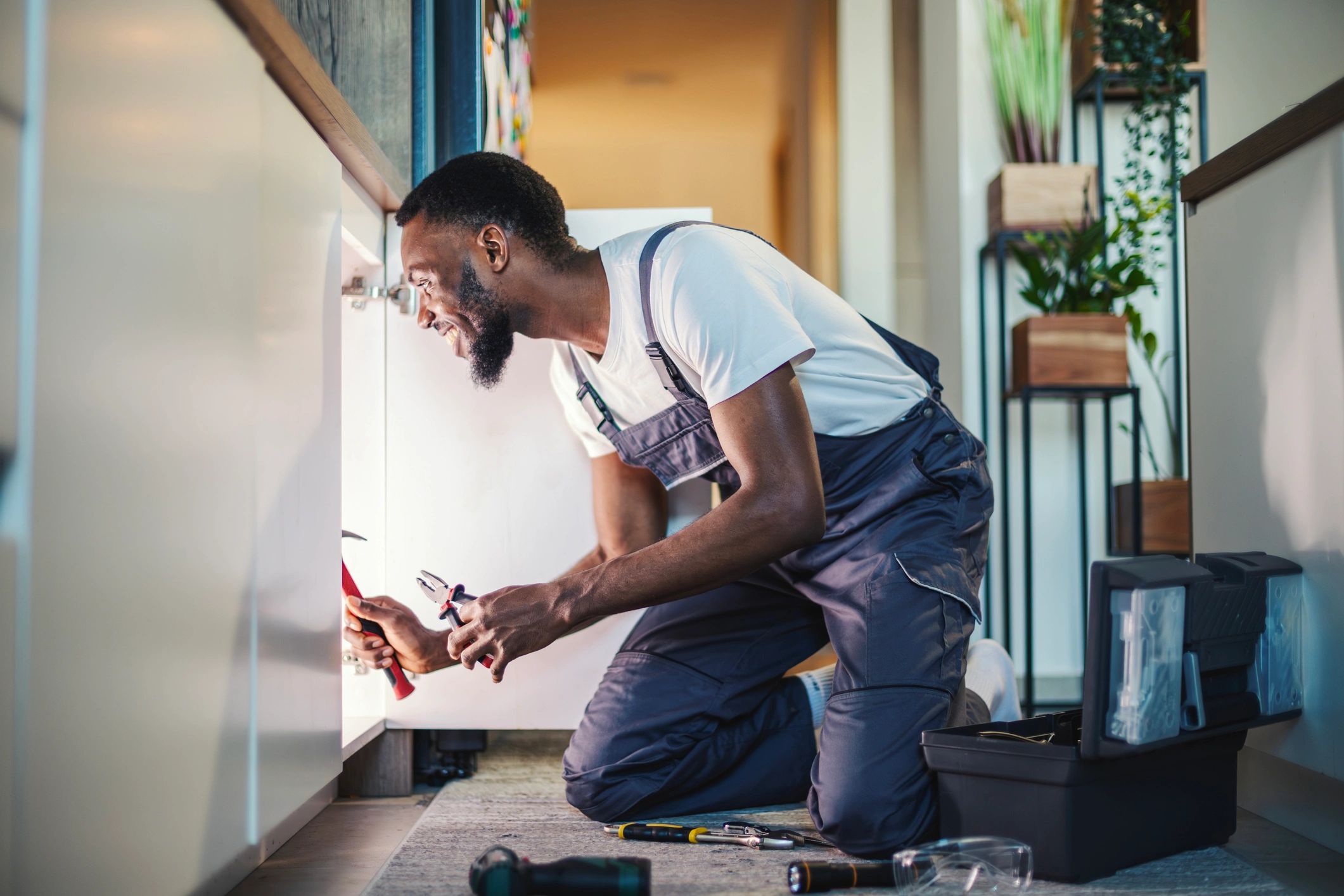 Handyman working under a kitchen sink to repair a leak